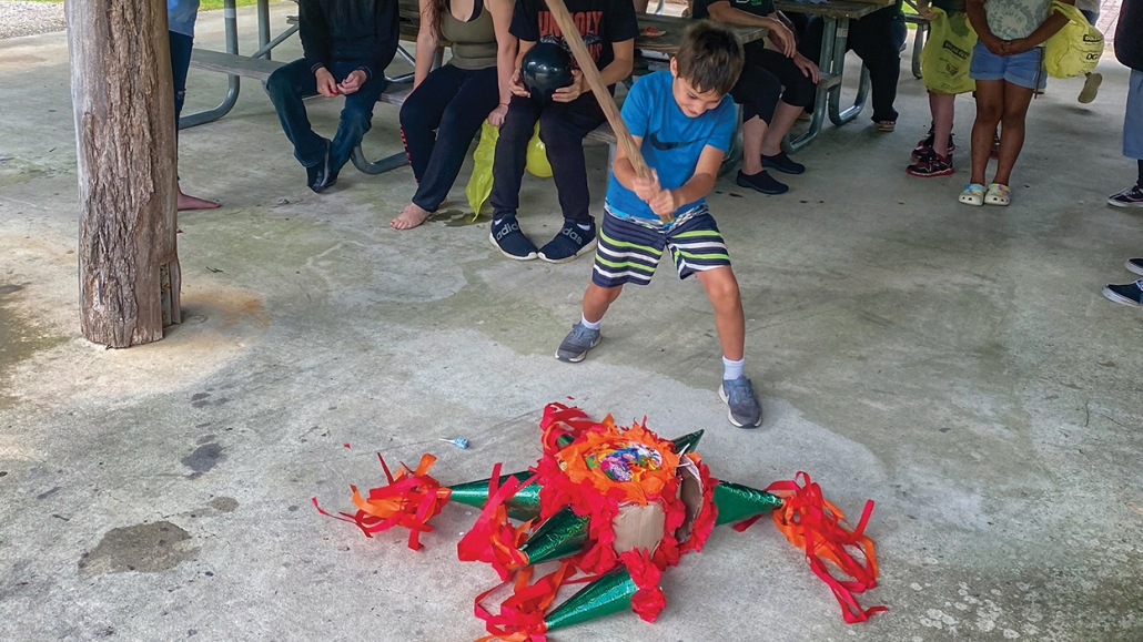 Little Brother Alex takes down the pinata at the 2021 Field Day event in June as onlooking Littles cheer him on!